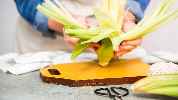 Passo dopo passo. sgusciare il mais biologico per fare la pannocchia di mais messicana elote.