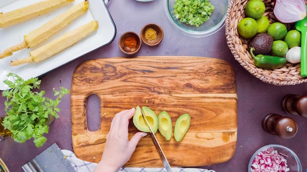 Photo step by step. slicing fresh avocado on a wood cutting board.