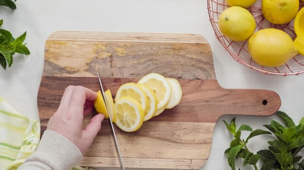 Step by step. Slicing organic lemon on wood cutting board.