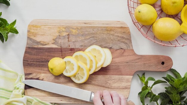 Step by step. Slicing organic lemon on wood cutting board.