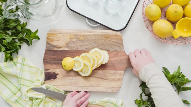 Photo step by step. slicing organic lemon on wood cutting board.