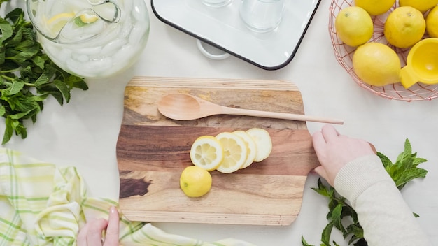 Step by step. Slicing organic lemon on wood cutting board.