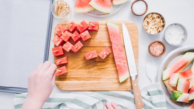 Step by step. Slicing watermelon into cubes for preparing chocolate covered watermelon bites.