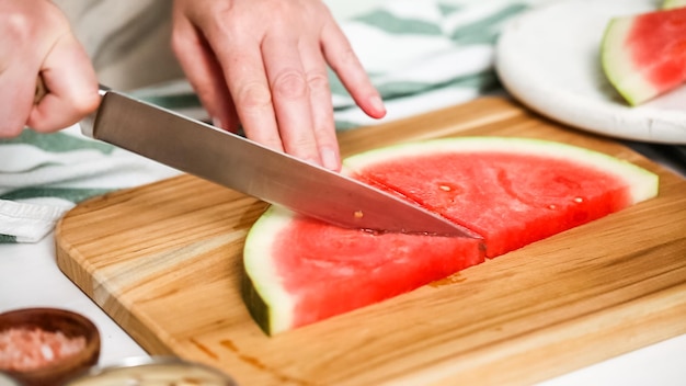 Step by step. Slicing watermelon into cubes for preparing chocolate covered watermelon bites.