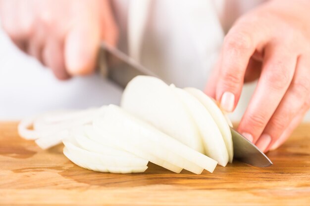 Step by step. Slicing yellow onion with kitchen knife on a cutting board.