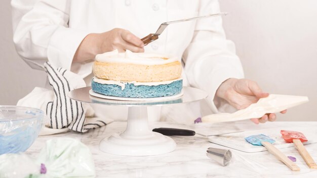 Step by step. Stacking cake layers to create the round three-layer vanilla cake.