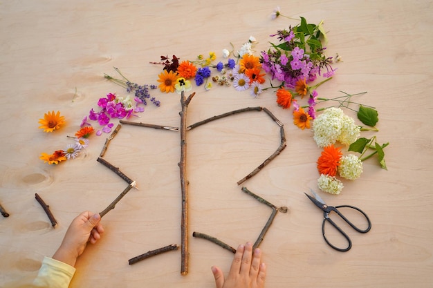 写真 花から作られた蝶のステップ・バイ・ステップ・チュートリアル 子供のための簡単な自然工芸 ステップ2 木製の棒で蝶の形を作る