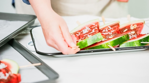 Step by step. Watermelon wedges garnished with chocolate and sea salt  on the stick on metal serving tray.