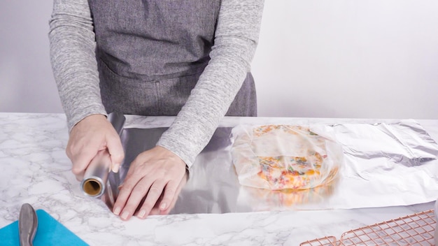 Step by step. Wrapping freshly baked funfetti cake into cellophane and cooking foil for freezer storage.