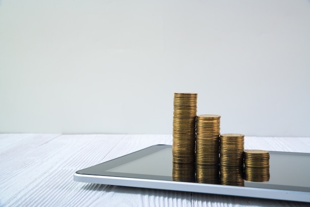 흰색 작업 테이블, 비즈니스 및 금융 개념에 태블릿 컴퓨터 화면에 동전 스택의 단계.