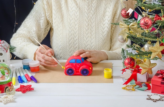 Stepbystep photo instruction of a Christmas decor a girl paints a plaster car step 6 coloring the headlights with yellow paint