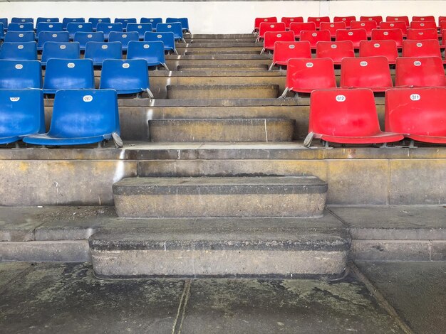 Foto passi in mezzo a sedie vuote rosse e blu allo stadio