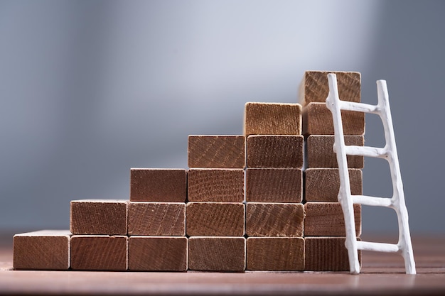 Steps made with wooden blocks on table against grey background