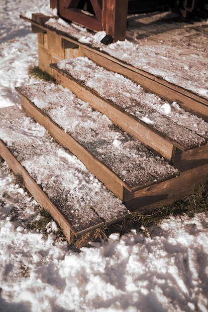 The steps of wooden stairs are covered with snow during a snowfall Descent to the yard of the house Cold day in the village