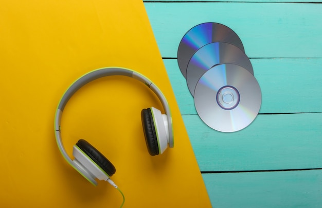 Stereo headphones, cd discs on blue wooden table