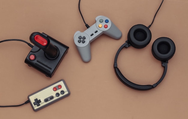 Stereo headphones and retro joysticks on brown background. Top view. Flat lay