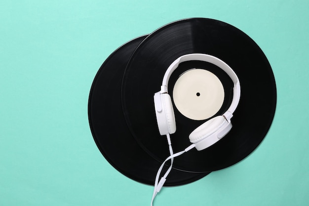 Stereo headphones and vinyl records on mint green background 80s Flat lay Top view