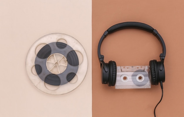 Stereo headphones with audio cassette and magnetic audio reel on brown beige background. top view