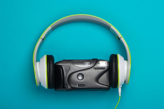 Stereo headphones with a retro film camera on a blue surface