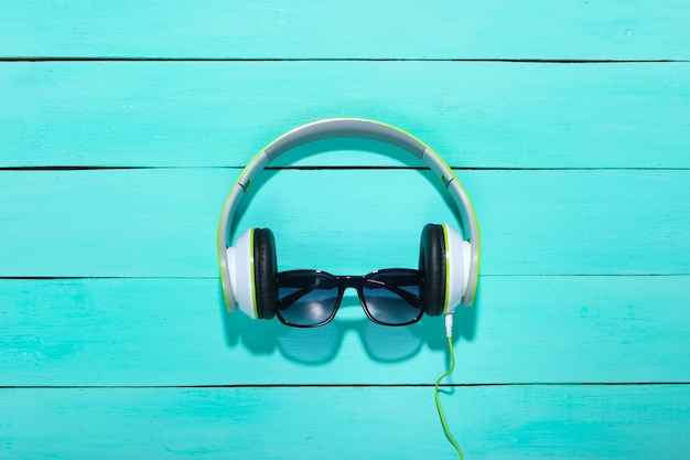 Photo stereo headphones with sunglasses on a blue wooden surface