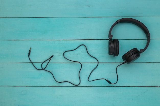 Stereo hoofdtelefoon met kabel op blauwe houten achtergrond. Bovenaanzicht