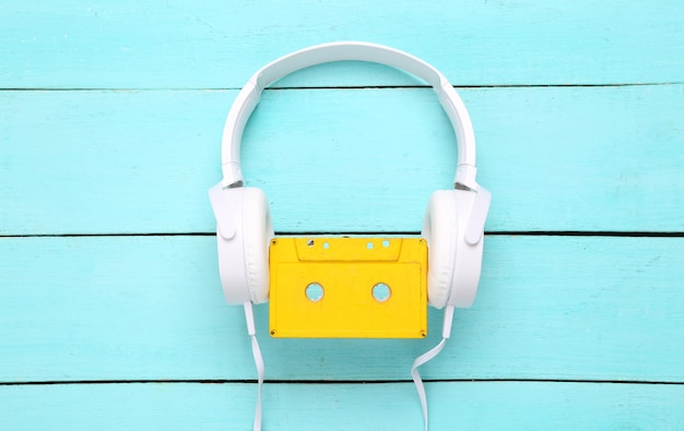 Stereohoofdtelefoon met audiocassette op een blauwe houten achtergrond Bovenaanzicht Minimalisme muziekconcept