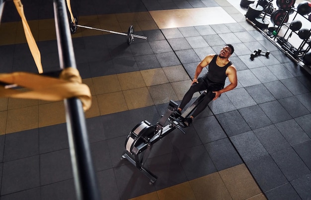 Sterke afro-amerikaanse man in sportieve kleding heeft een trainingsdag in de sportschool en gebruikt apparatuur Conceptie van kracht en kracht