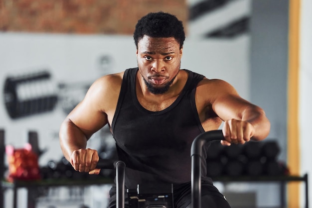 Sterke Afro-Amerikaanse man in sportieve kleding heeft een trainingsdag in de sportschool met behulp van apparatuur