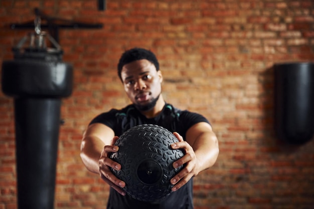 Sterke Afro-Amerikaanse man in sportieve kleding in de sportschool en bal in handen houden