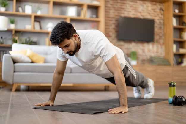 Sterke Arabische mens die plankpositie op yogamat doet