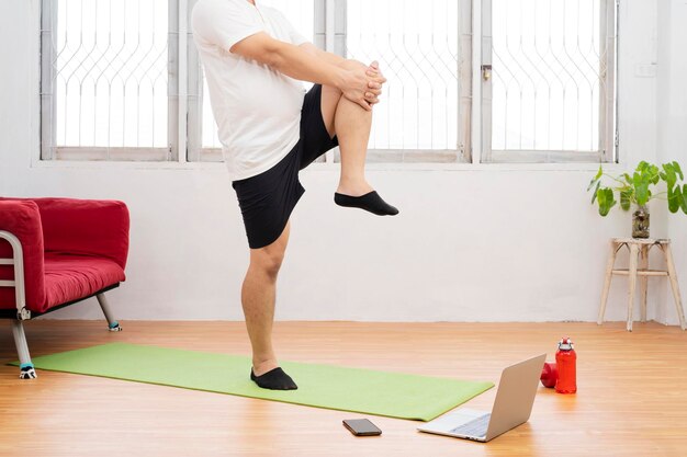 Sterke atletische fitte man in t-shirt en korte broek is energiek aan het joggen op zijn plaats thuis