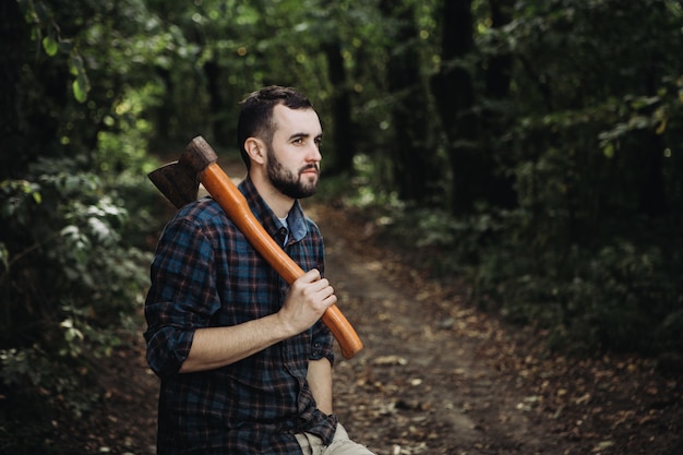 Sterke bebaarde houthakker houdt een bijl in het bos