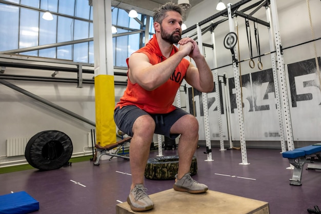 Sterke blanke workout met houten doos in de crossfit sportschool