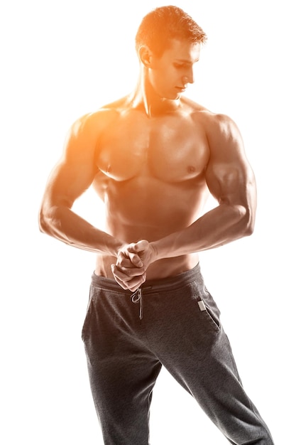 Sterke bodybuilder man poseren met perfecte buikspieren, houders, biceps, triceps en borst. Geïsoleerd op witte achtergrond Met zonnevlam