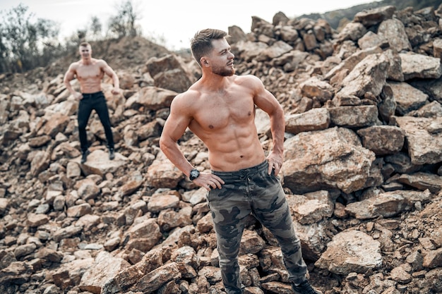 Sterke bodybuilders trainen buiten met naakte torso Shirtloze mannen in goede vorm en gespierde torso