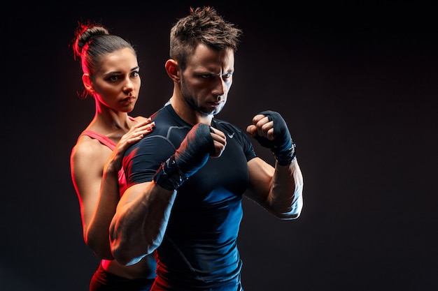 Sterke bokser in houding met handwraps op zijn vuisten met vriendin achter hem.