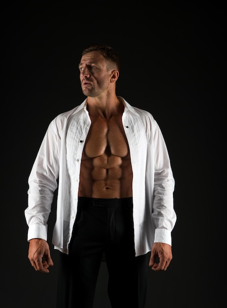 Sterke en elegante gespierde man zwarte achtergrond Formele stijl Mode garderobe Trendy herenkleding Kledingvoorschrift Knappe man toont zes pack buikspieren in open shirt Wellness en lichaamsverzorging Sport en gezondheid