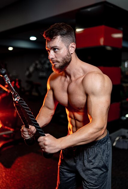 Sterke en harde jonge gespierde blanke atleet traint in de sportschool. Man doet krachtoefeningen, oefent, poseert zelfverzekerd en toont spieren. Fitness, wellness, gezond levensstijlconcept.