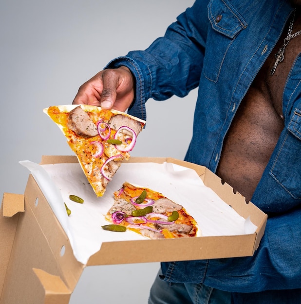 Sterke gespierde handen houden pizza in handen Selectieve bijgesneden foto van een hongerige onherkenbare Afro-Amerikaan met pizza in een doos Close-up
