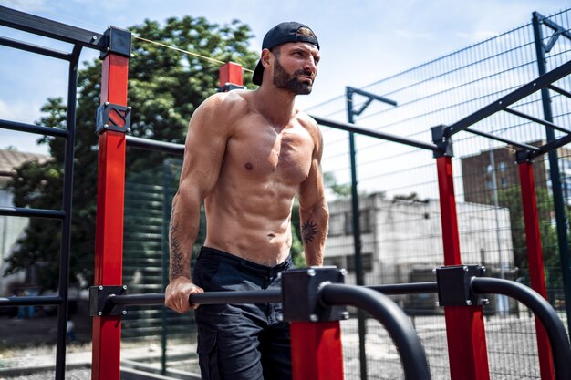 Sterke gespierde man doet push-ups op ongelijke bars in de straat street gym