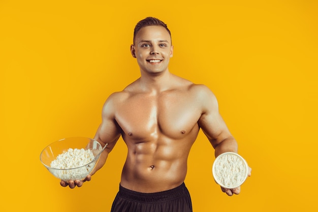 Sterke gezonde man die zich voordeed op een zwarte achtergrond bodybuilder atleet houdt kwark het concept vast