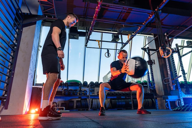 Sterke jonge man die hard werkt in de sportschool Atletische gezonde mannen die samen trainen