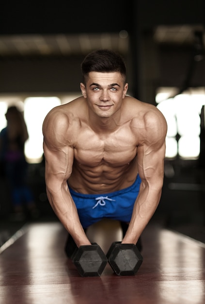 Sterke, knappe man doet push-ups op halters in een sportschool als bodybuilding-oefening, zijn spieren trainen