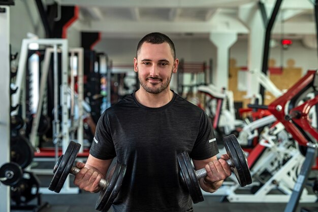 Sterke knappe mannentrainer in sportieve, getailleerde kleding traint zijn klanten om de gezondheid te verbeteren