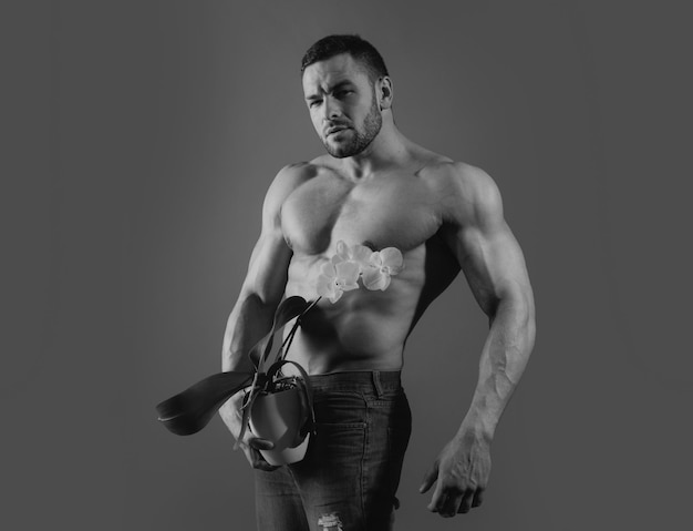 Sterke man houdt orchidee vast en toont zijn perfecte naakte lichaam, naakte torso, modeportret van jonge, hete nake