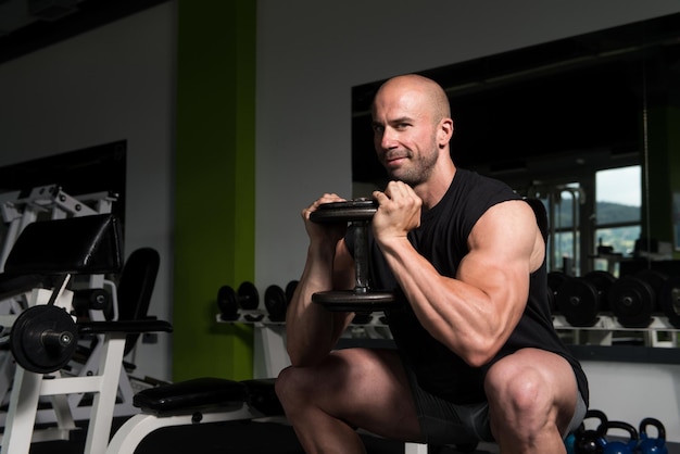 Sterke Man In de sportschool uitoefening van quadriceps en billen met halters gespierde atletische bodybuilder Fitness Model oefening