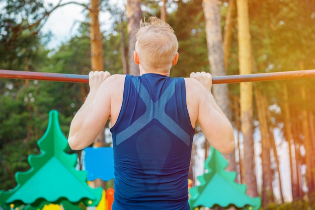 Sterke man pull-ups op een balk buiten doen