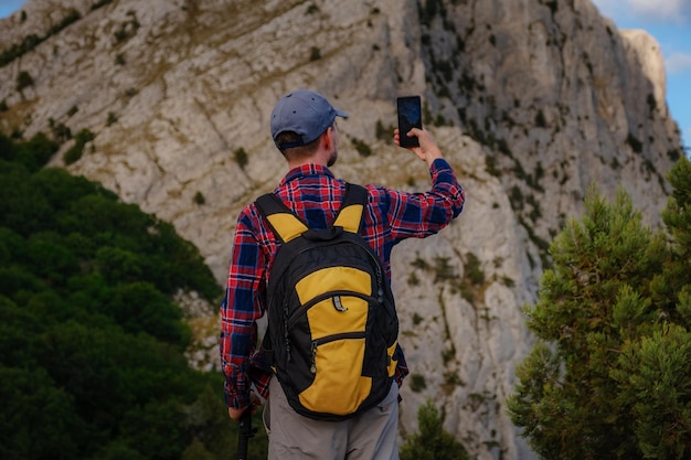 Sterke man wandelaar fotograferen met smartphone op bergtop