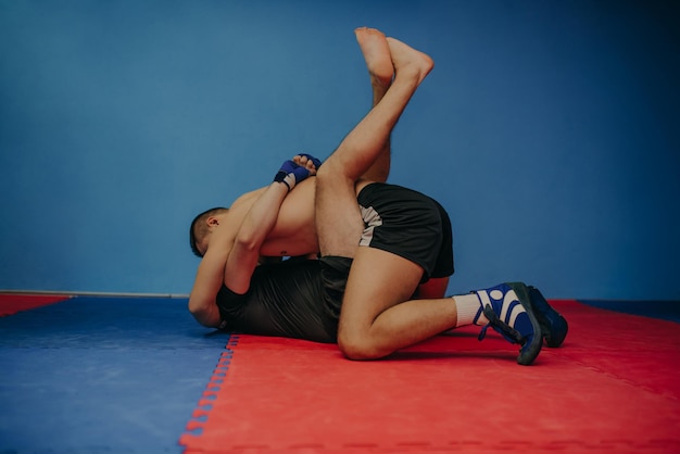 Sterke MMA-jager die zijn rivaal vasthoudt en stoten naar hem gooit tijdens een training Met veel kopieerruimte