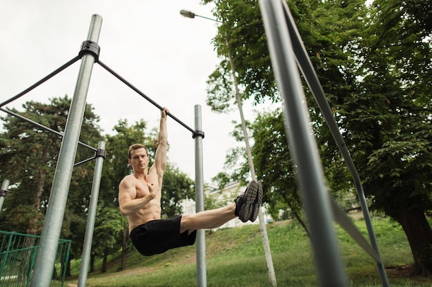 Sterke shirtless blanke atleet die hoek uitvoert op horizontale balk